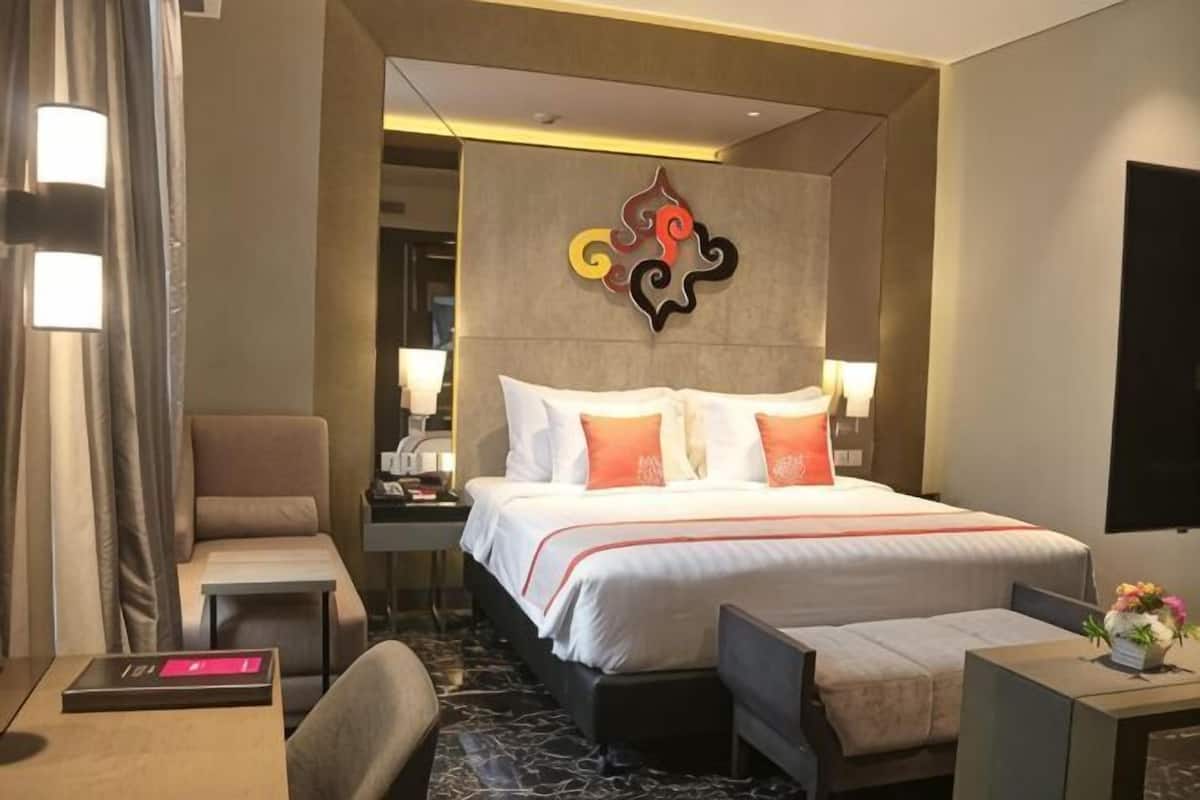Quarto de hotel com uma cama grande, mesas de cabeceira, escrivaninha e uma cadeira.