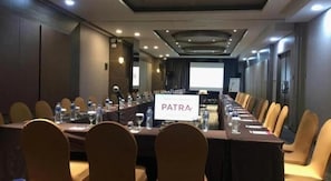A conference room with a long table, chairs, water bottles, and a screen displaying 'PATRA'. - Patra Cirebon (Kedawung)