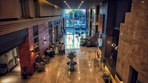 Een ruime lobby met een hoge plafond, een centraal zitgedeelte en uitzicht naar buiten.