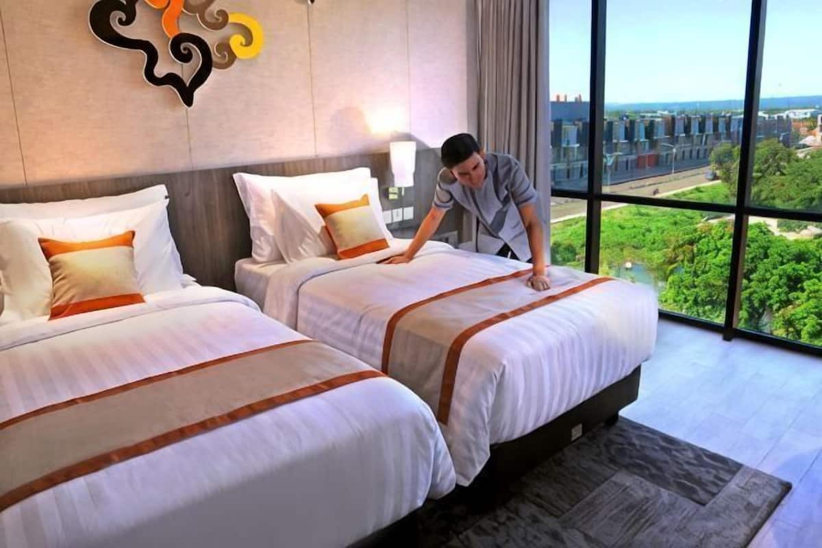 Quarto de hotel com duas camas, uma janela grande com vista para a cidade e decoração moderna.