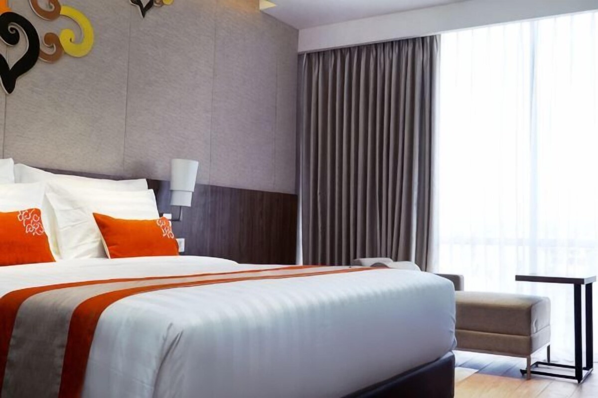 A hotel room with a large bed, a chair, a table, and a view of the outdoors.