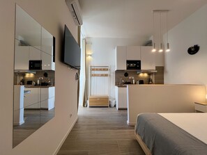 Una camera d'albergo moderna e funzionale, con angolo cottura, un letto e una televisione.