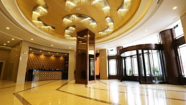 A spacious lobby with a polished floor, a reception desk, and a large, curved glass entrance. - UPLS Hotel (Zhongwei)