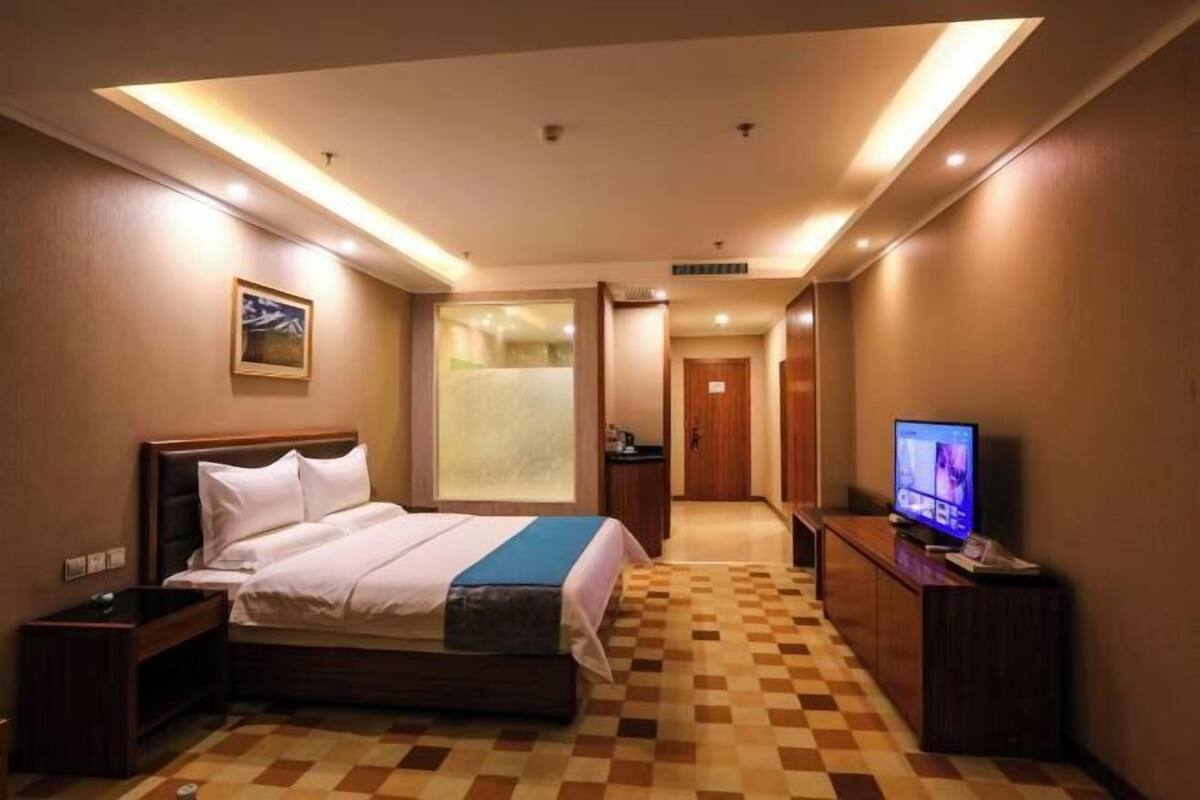 A hotel room with a bed, a television, a nightstand, and a check-in counter.