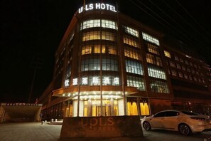 Et hotel med en buet facade, oplyst skiltning og en markant indgang.