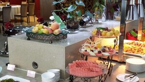 A buffet area with various food items, including fruits and vegetables, arranged on a counter. - UPLS Hotel (Zhongwei)