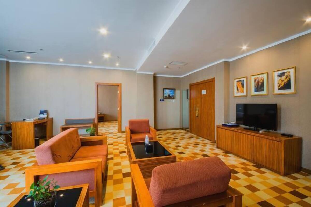 A hotel lobby with a checkered floor, wooden furniture, a television, and framed pictures on the wall.