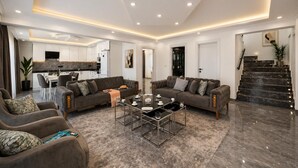 Una sala de estar moderna con un conjunto de sofás, una mesa de centro y una escalera.