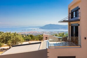 Ein modernes Gebäude mit einem Balkon mit Blick auf eine Küstenstadt und das Meer.
