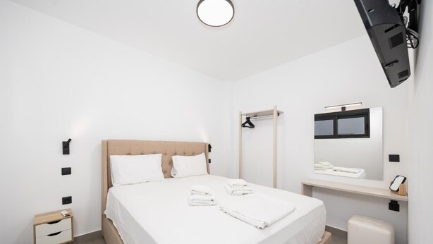 Una habitación de hotel moderna con cama, mesitas de noche, un espejo y una ventana.