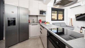 A modern kitchen with stainless steel appliances, a built-in water dispenser, a microwave, and a large window offering a view of the outdoors.