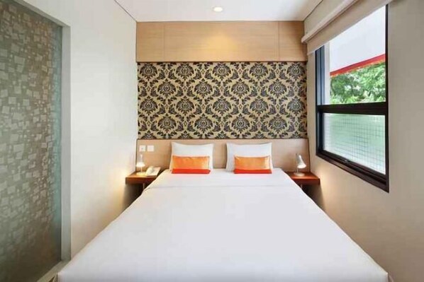 A hotel room with a large bed, two bedside tables, a patterned headboard, and a window with a view. - De Sofia Dago (Coblong)