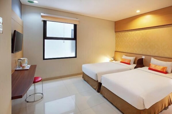 A hotel room with two beds, a desk with a chair, a television, and a window. - De Sofia Dago (Coblong)