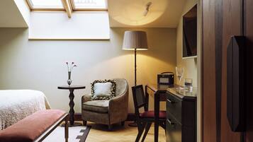 A bedroom with a bed, a chair, a desk, a lamp, and a TV.