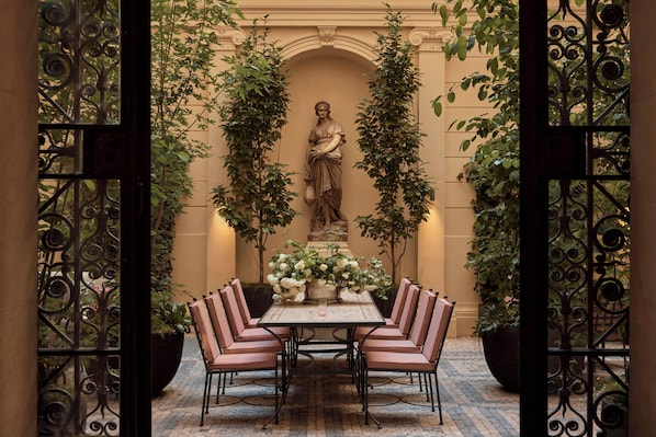 A dining area with a table set for four, surrounded by chairs, and a statue in the background. - Sir Prague, part of Sircle Collection (Prague)