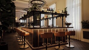 Eine Bar mit einer langen Theke, mehreren Hockern und einer Auswahl an Flaschen und Gläsern.