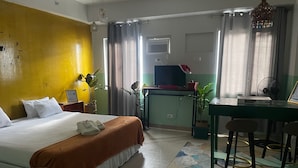 A hotel room with a bed, a desk, a chair, a TV, and a fan. - Poolside Apartment - Sleeps 4, Ac & Hot Shower (Marilao)