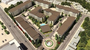 An aerial view of a residential complex with multiple apartment buildings, a central landscaped area with a circular feature, and surrounding greenery. - Poolside Apartment - Sleeps 4, Ac & Hot Shower (Marilao)
