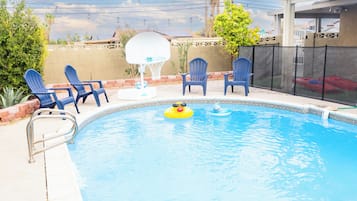 Una piscina con sillas azules y un aro de baloncesto.