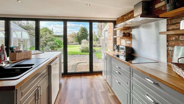 A modern kitchen with a large sliding glass door leading to a garden.