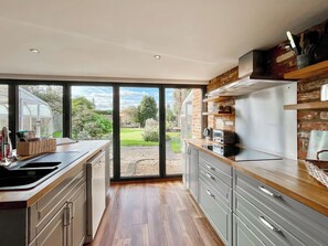 A modern kitchen with a large sliding glass door leading to a garden.