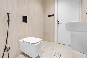 A modern bathroom with a toilet, a shower, and a door. - Silkhaus Al Mahmal 70 (Riyadh)
