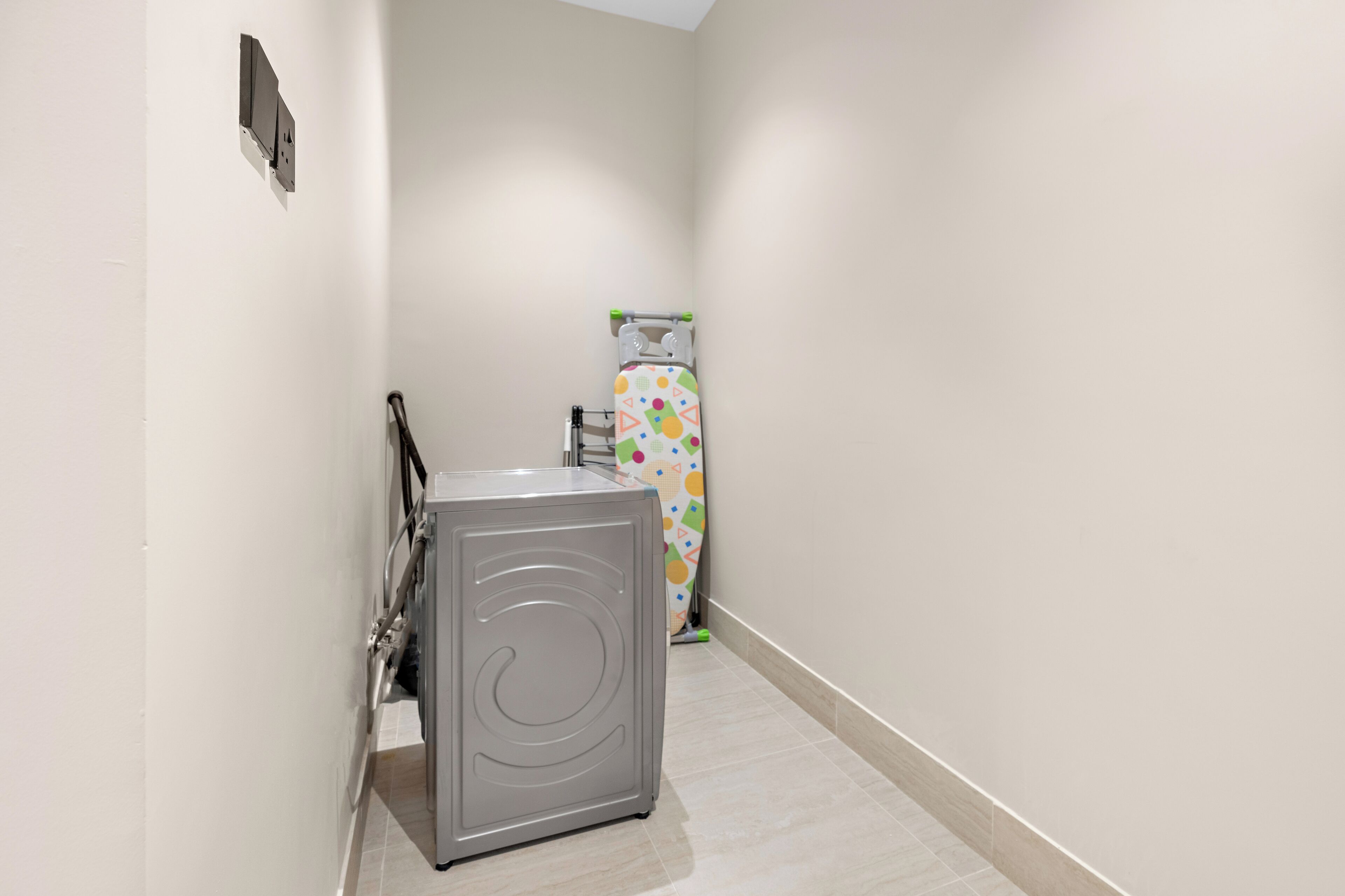 A narrow hallway with a grey appliance, possibly a washer, and a colorful appliance in the background.