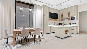 A modern kitchen with a central island, built-in appliances, and a dining area with a table and chairs.