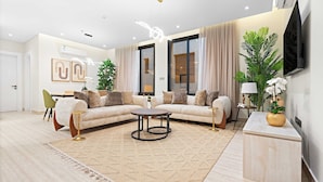 Uma sala de estar moderna com um sofá seccional, uma mesa de centro redonda e uma grande planta em vaso.
