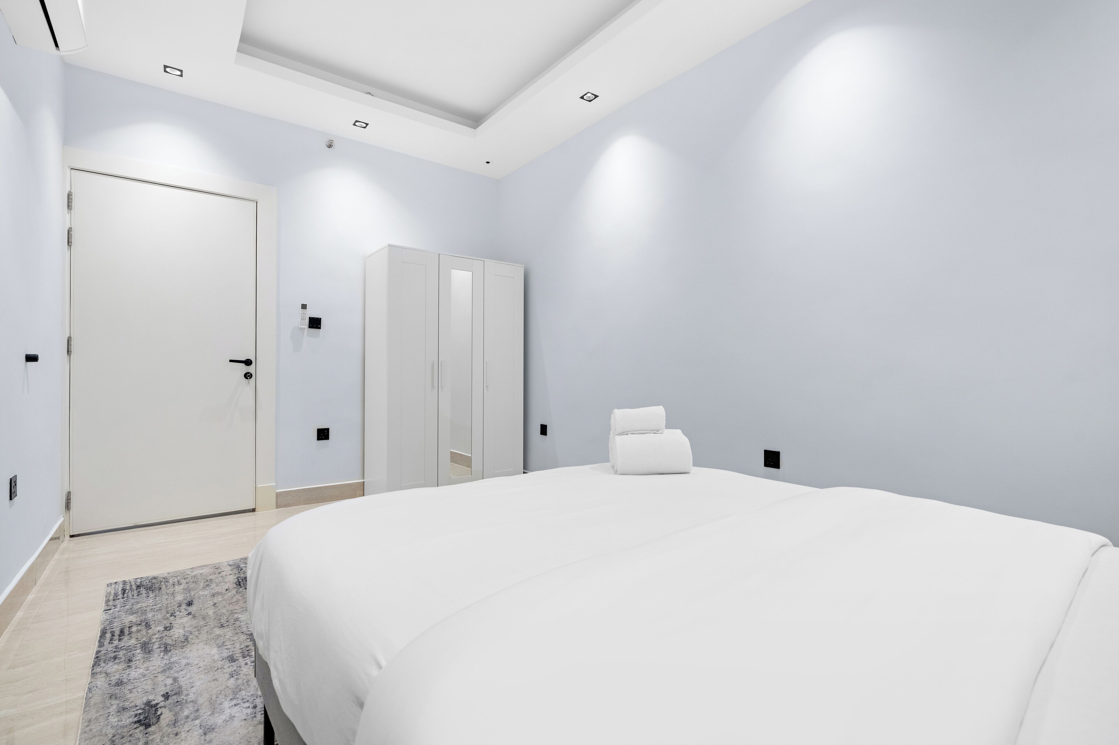 A modern bedroom with a large bed, a wardrobe, and a door.