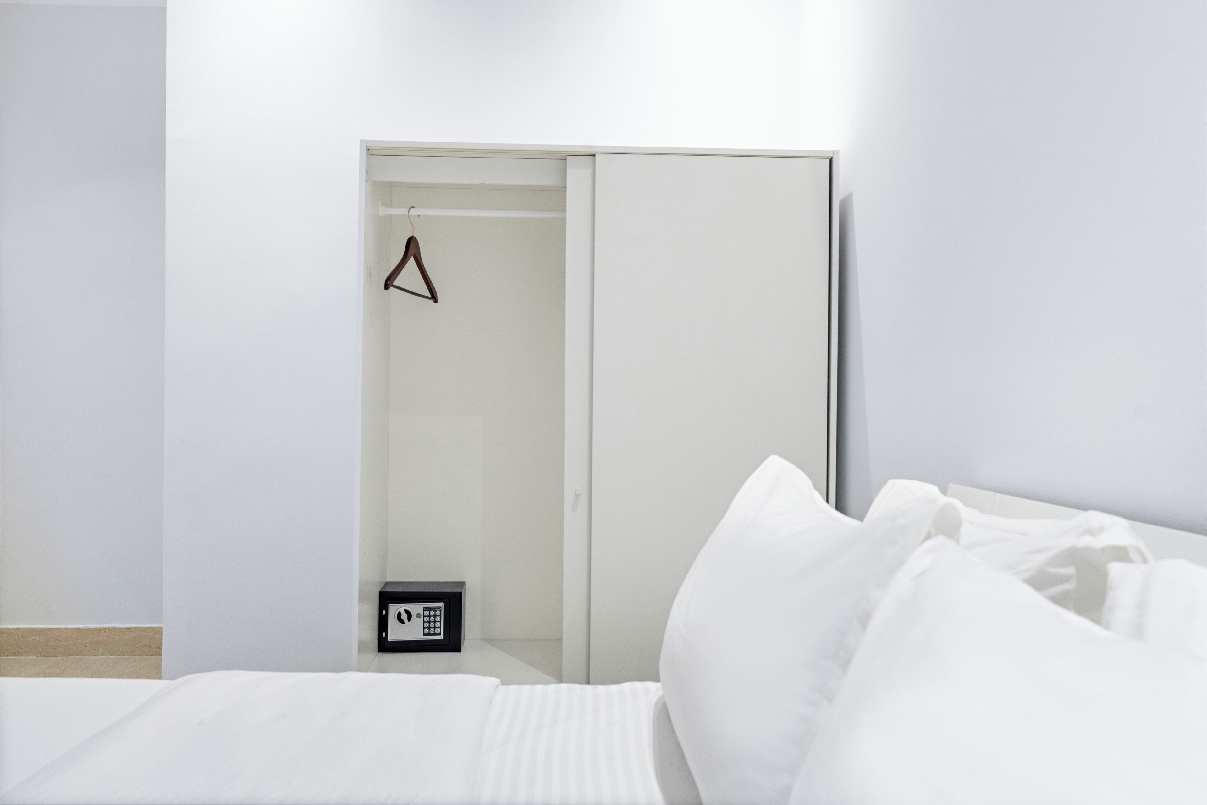 A hotel room with a bed, a wardrobe, and a small bedside table with a phone.