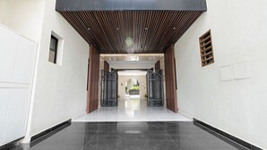 A modern building entrance with a reflective black floor, metal gates, and a wooden slatted ceiling. - Silkhaus Sayl 25 (Riyadh)