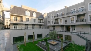 A modern multi-story building with balconies, a central courtyard with a small tree, and a staircase leading to the upper floors. - Silkhaus Majidia 127 (Riyadh)