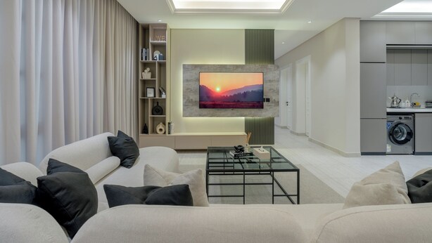 A modern living room with a sofa, a coffee table, and a TV mounted on the wall. - Silkhaus Majidia 127 (Riyadh)