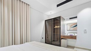 Et moderne hotelværelse med en stor seng, et walk-in closet, et badeværelse med et spejl og et billede på væggen.