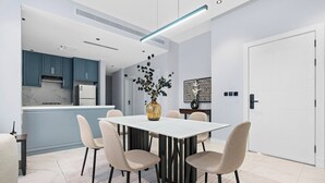 A modern dining area with a white table, beige chairs, and a vase with green foliage. - Silkhaus Majidia 139 (Riyadh)