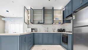 A modern kitchen with blue cabinets, a stainless steel refrigerator, and a marble countertop. - Silkhaus Majidia 139 (Riyadh)