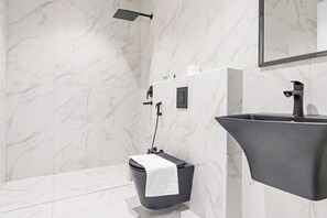 A modern bathroom with a marble wall, a black sink, and a handheld showerhead. - Silkhaus Majidia 139 (Riyadh)