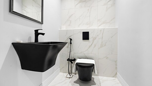 A modern bathroom with a black sink, a toilet, and a shower area.