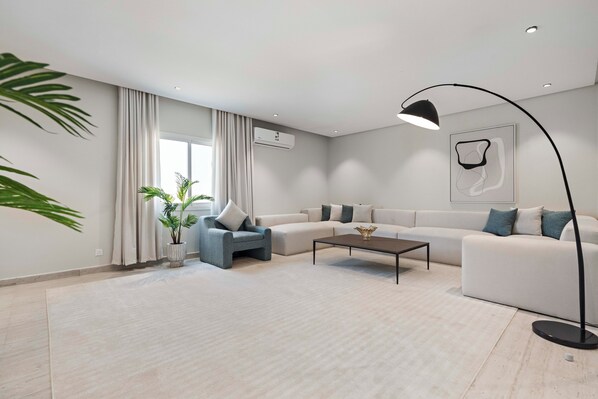 Una sala de estar moderna con sofá, sillón, mesa de centro y lámpara de pie.