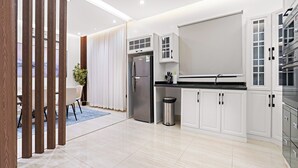 A modern kitchen with white cabinetry, stainless steel appliances, and a black countertop. - Silkhaus Majidia 77 (Riyadh)