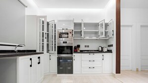 A modern kitchen with white cabinetry, stainless steel appliances, and a black countertop. - Silkhaus Majidia 77 (Riyadh)