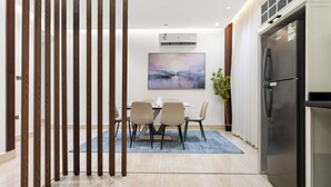 A modern kitchen with a dining area, featuring a large refrigerator, a dining table with chairs, and a blue rug. - Silkhaus Majidia 77 (Riyadh)