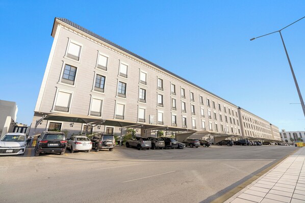 Ein großes, mehrstöckiges Hotel im klassischen Stil, mit einer Reihe von Balkonen und einem überdachten Parkbereich.