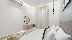 A modern bedroom with a bed, bedside table, and a wall-mounted air conditioner. - Silkhaus Majidia 77 (Riyadh)