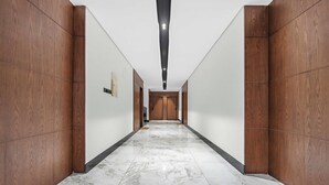 A hallway with wooden panel walls, a marble floor, and recessed lighting. - Silkhaus Rose Residency 36 (Riyadh)