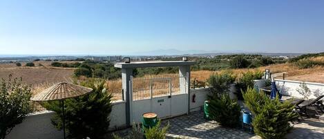 A patio area with a table and chairs, a small covered seating area, and a view of the landscape.