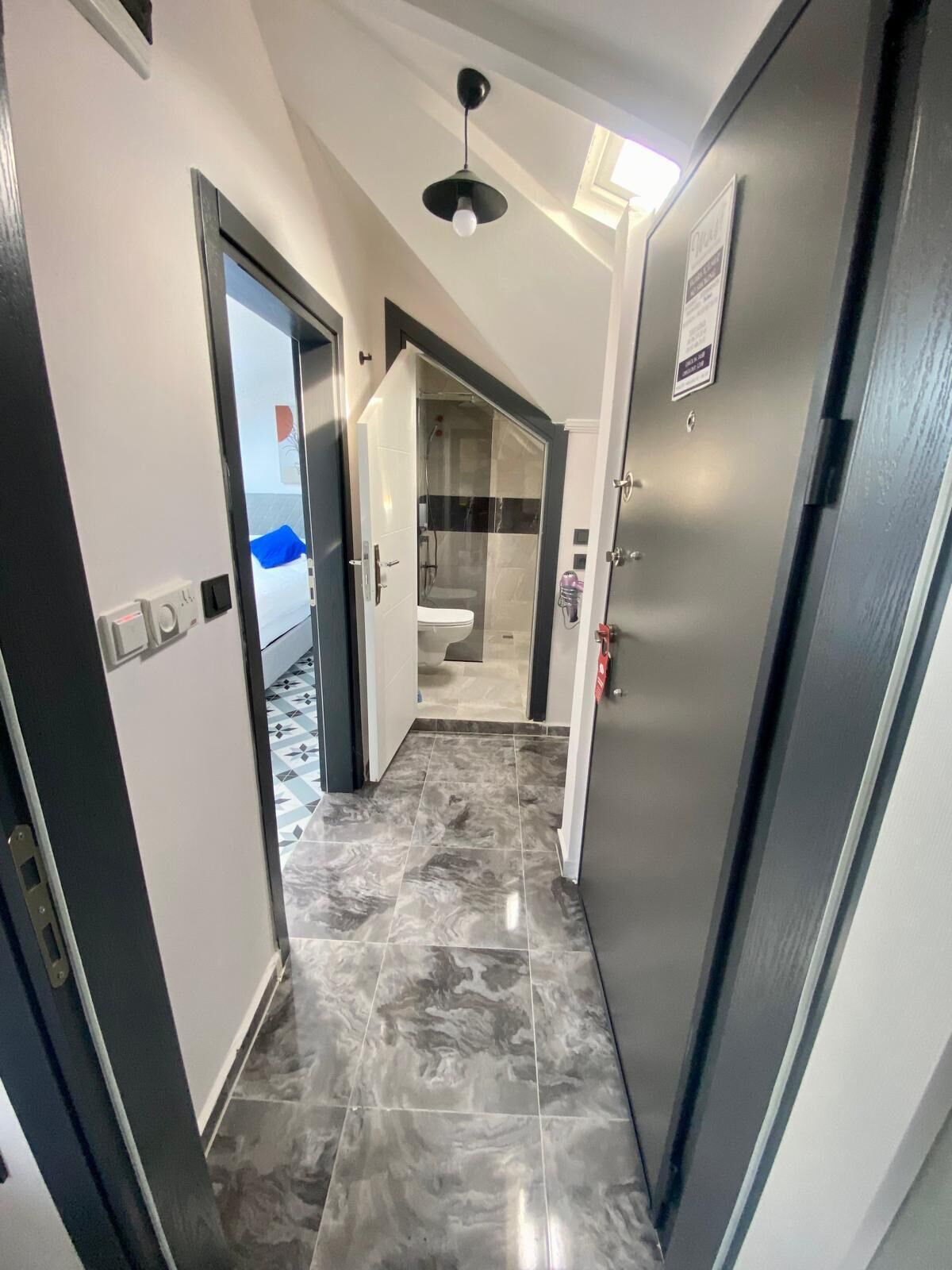Un pasillo con piso de mármol que conduce a un baño con cabina de ducha de vidrio.
