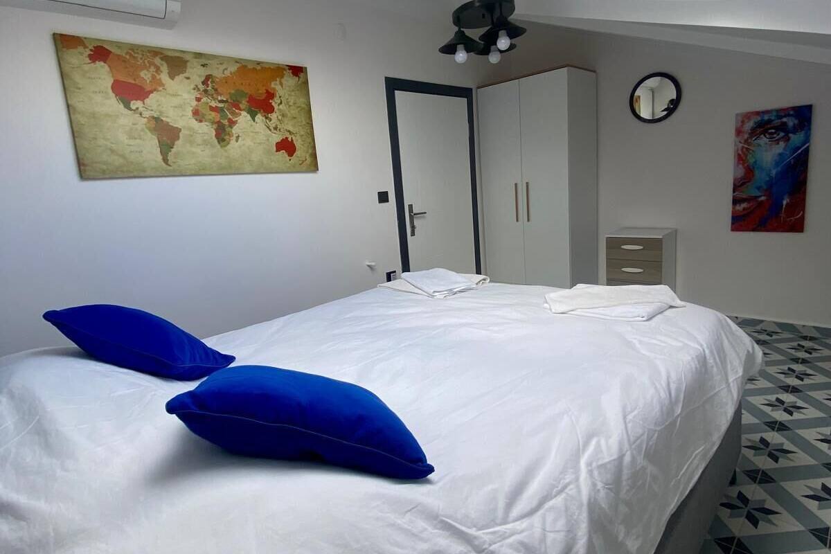 A bedroom with a bed, a skylight, a map, a clock, and a painting.