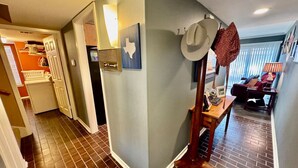 Un couloir comprenant un coin cuisine, un coin repas et un porte-manteau avec des chapeaux.